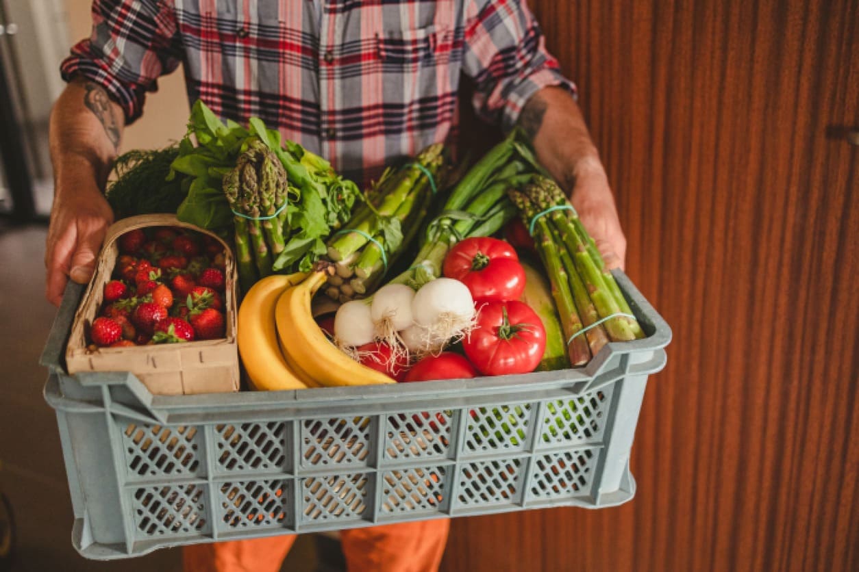 hombre con caja de frutas y verduras